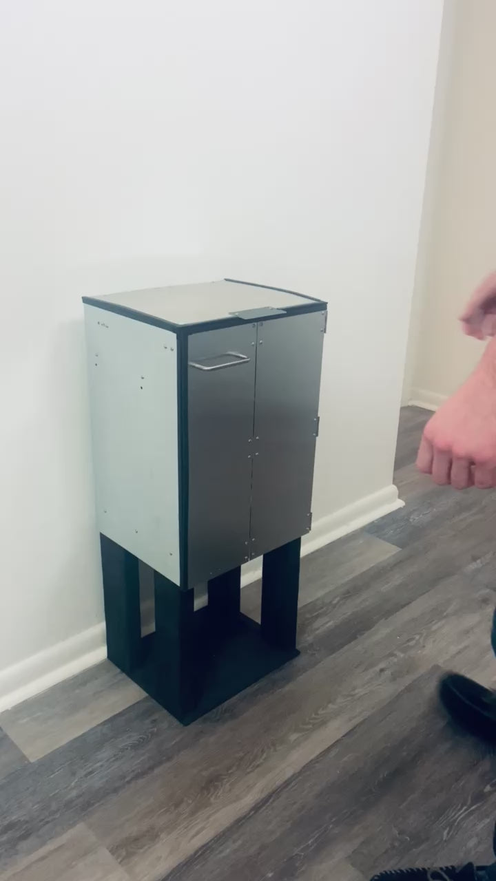 The DorrCan trash can in a kitchen being operated, the lid and doors are opened, the retainer rack is moved out of the way, the bag is cinched closed and then removed outwards horizontally from the trash can